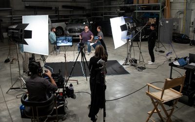 Équipe de production filmant une vidéo de trois personnes parlant devant deux camions.